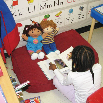 Little girl reading to 2 cabbage patch kids