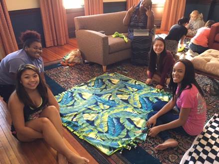 Girls sitting on the floor around a blanket