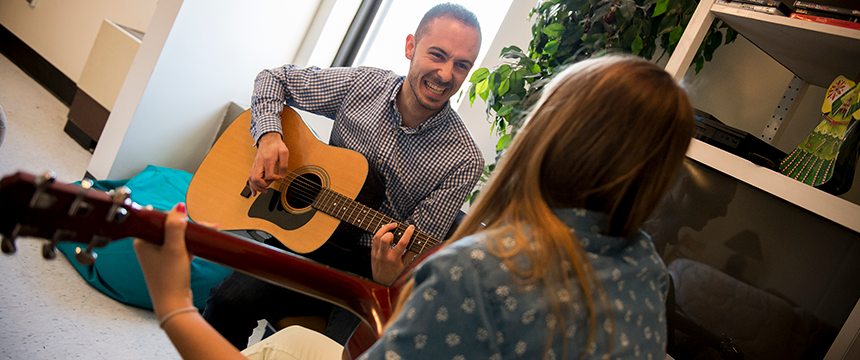 Man and woman smile and play guitars