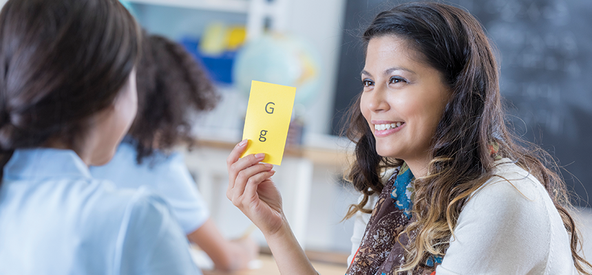 Teacher holding a flashcard with letter "g" up for student