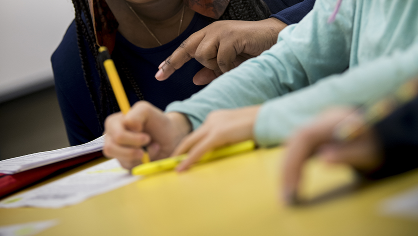 Hands of teacher and student using pencil and paper