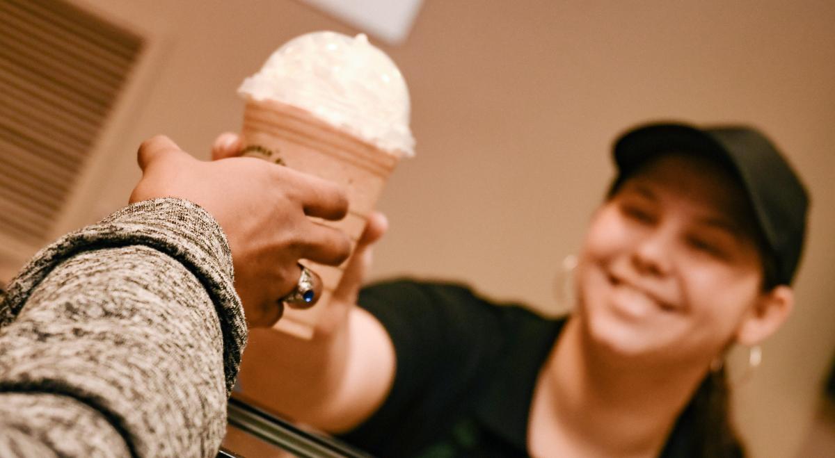 A woman handing a cup of coffee