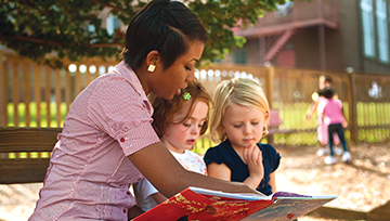 Teacher reading to kids on a park bench