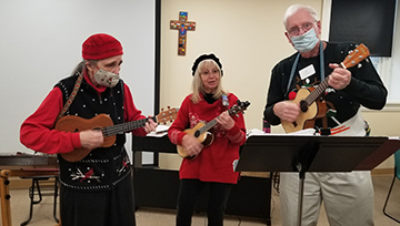 Three Renaissance Institute members play music with guitars.