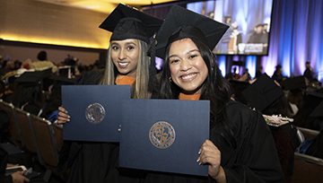 Two members from the Class of 2022 pose with their diplomas