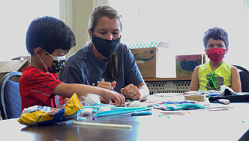 An instructor works with two children during Notre Dame's STEM camp in 2021