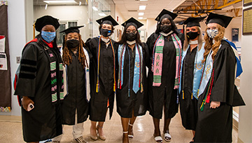 students and staff pose for group photo in cap & gown