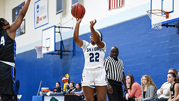 An NDMU basketball player attempts a 3-pointer