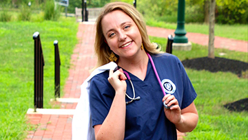 An outdoor photo of Jen Dickensheets in her nursing scrubs.
