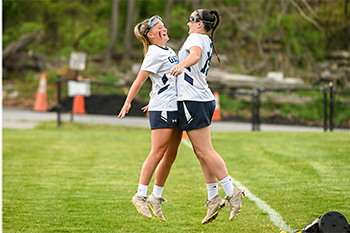 Two Lacrosse students chest bumping