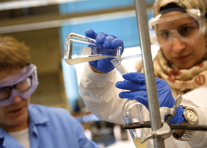 Student and faculty member conducting chemistry experiment