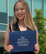 Jolisse holding a blue folder that says "The Fund for American Studies"