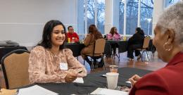 Female student smiling while sitting at a table across from another person