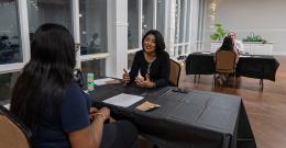 Female student smiling while sitting at a table across from another person