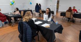 Female student smiling while sitting at a table across from another person