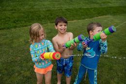 three kids playing water gun on the lawn