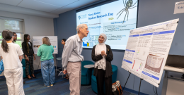 Female student presents poster to a male faculty member