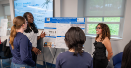 Female student presents poster to several female students