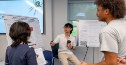 Male student presents poster to male students