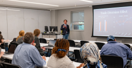 Male student presents his research to an audience while standing at a podium