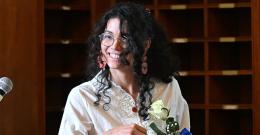 Student stands at a podium holding a white flower