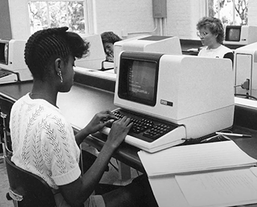 Black & white photo of students in a computer lab with old computers