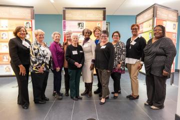 Women leaders in front of exhibit