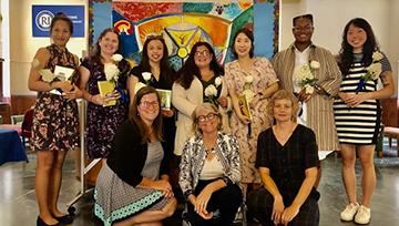 Art therapy graduates pose holding white flowers