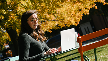 Student outside on campus with a laptop