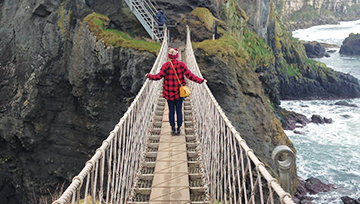 Student on a rope bridge on a mountain next to the water