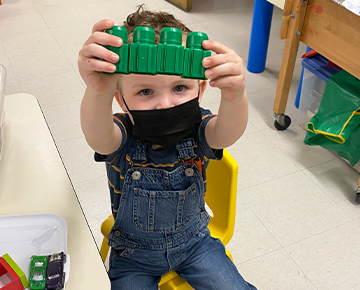 Young boy wearing a mask and holding up blocks