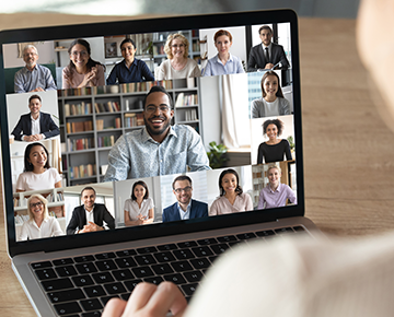 virtual meeting on a laptop with lots of faces