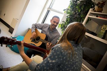 Man and woman smile and play guitars