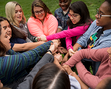 group of students crossing arms and holding hands