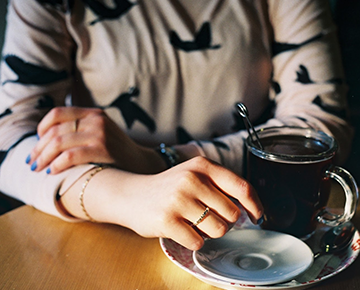 cropped photo of a girl holding a coffee cup (no face visible)