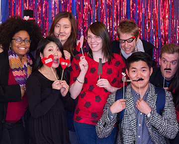 Group of students in a photo booth with silly props