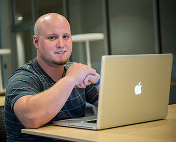 Male student sitting next to a laptop