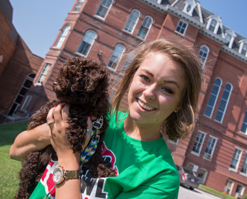 Girl holding a puppy on campus
