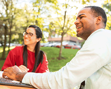 Male and female students studying outside on a sunny day