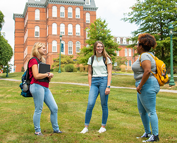 Three women on the front lawn of Gibbons Hall