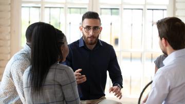 A man is talking to a group of people sitting in a circle