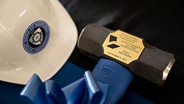 An NDMU hard hat next to a commemorative sledgehammer