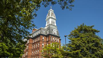 Trees surround a brick building with a white tower