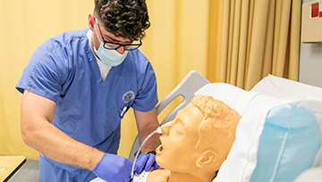 Male nursing student works with breathing tube on manikin