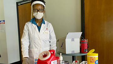 Pharmacist wearing a mask and shield with flu shot supplies