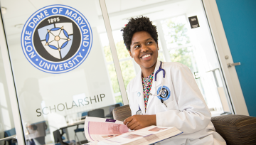 Nursing student sitting in front of NDMU seal