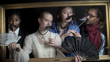 Actresses in a picture frame holding props and wearing historical clothing