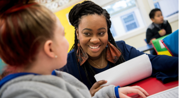 Female teacher smiles at a young student in a classroom