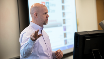 Professor teaching in front of a projector screen