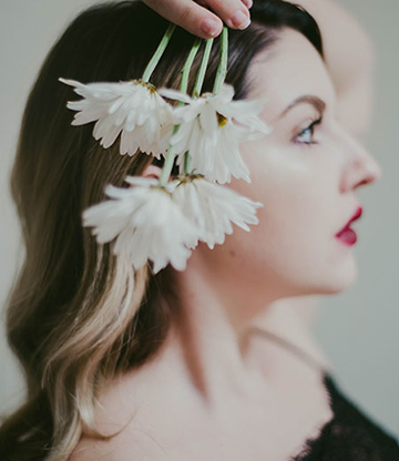 Woman poses holding white flowers next to her head